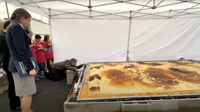 People gather around as a judge measures the world's largest grilled cheese