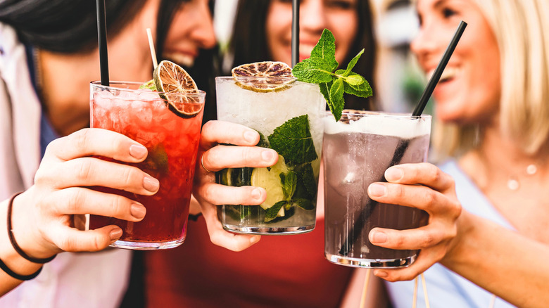A closeup of three friends holding cocktails.