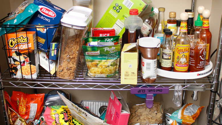 Cluttered food fills the shelves of a metal pantry shelving unit