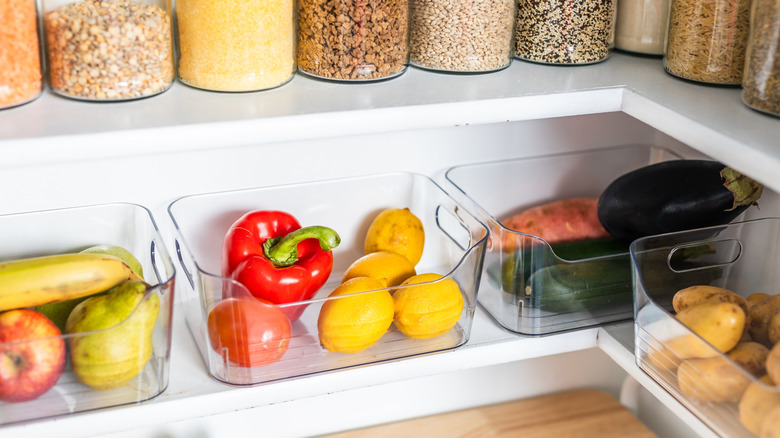 Produce and grains arranged in containers on white pantry shelves