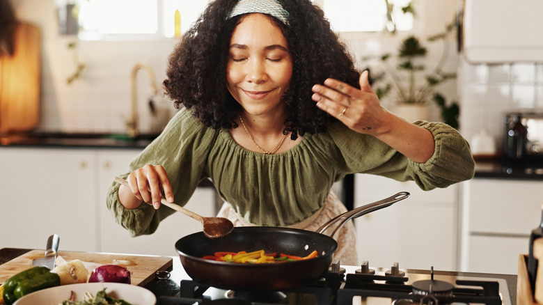 A woman cooking and smelling the aroma from the pan