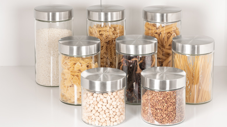 Glass jars containing assorted dry foods arranged on a white shelf
