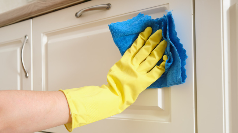 A woman wiping a kitchen cabinet