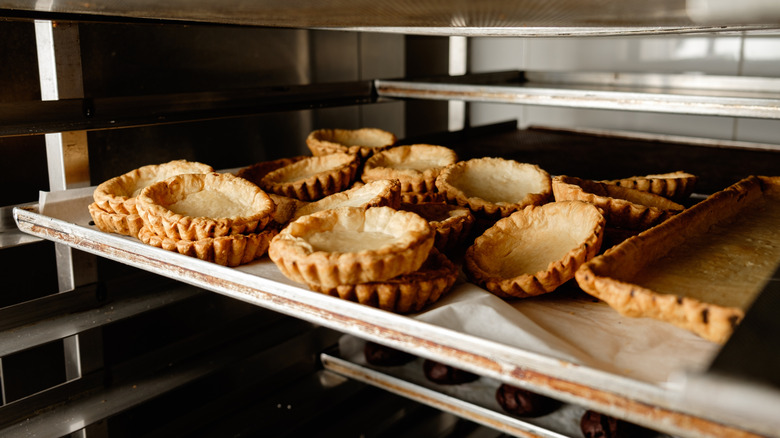 Golden brown tart shells piled on a baking rack