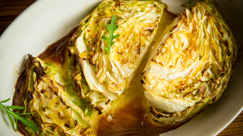 Cabbage wedges in roasting dish with liquid.