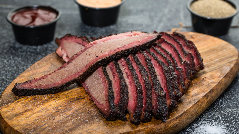 A platter of sliced beef brisket with sauces