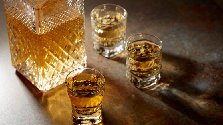 A decanter and small glasses of whiskey.