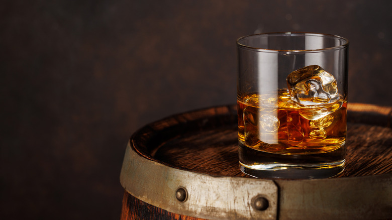 A classic whiskey glass placed on a wooden barrel.