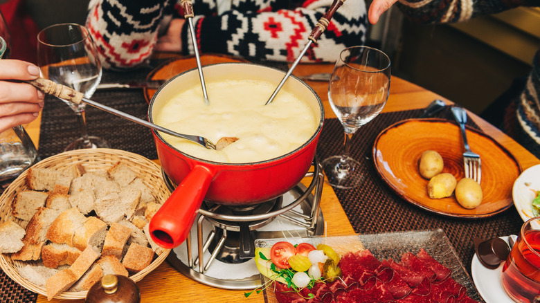 People dipping fondue forks into cheese fondue