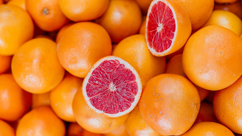 A sliced grapefruit on top of many whole grapefruits