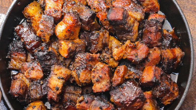 A closeup of pork belly pieces that are perfectly charred in a pan