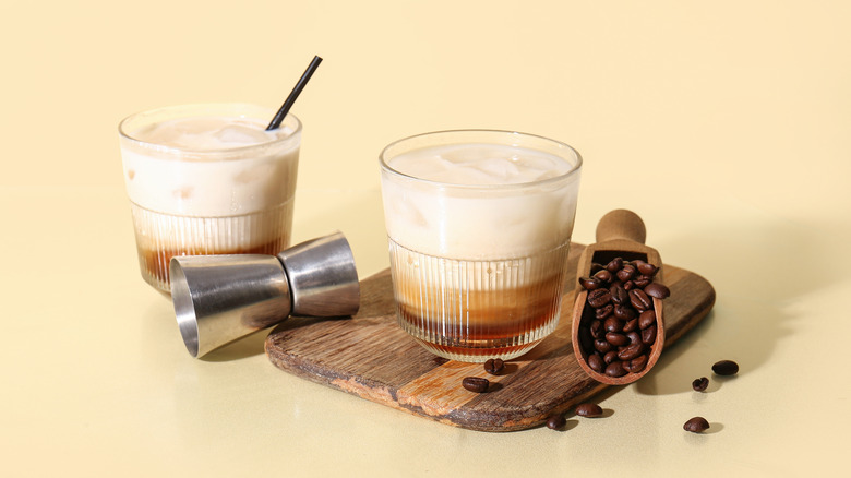 Two coffee cocktails with wooden cutting board and coffee beans.