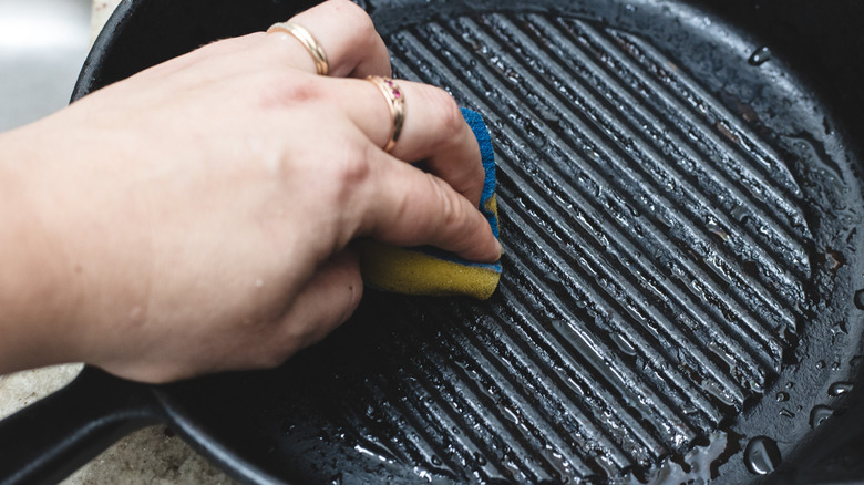Scrubbing a cast iron pan with a sponge