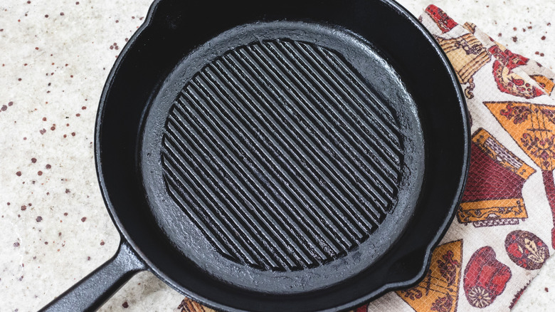 Clean cast iron pan with a cloth on marble countertop
