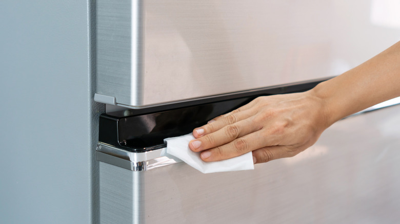 Hand wiping down the refrigerator door