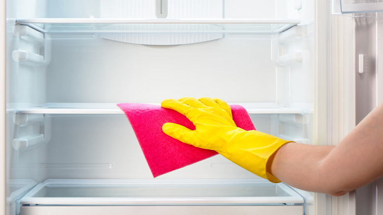 Hand wearing a glove cleaning the fridge