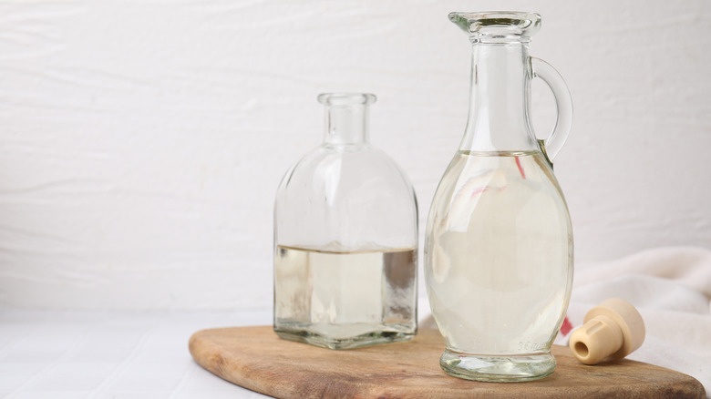 bottles of white vinegar on a wooden cutting board