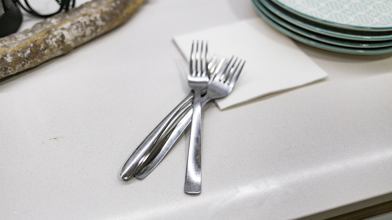 Several silver forks on a kitchen counter.