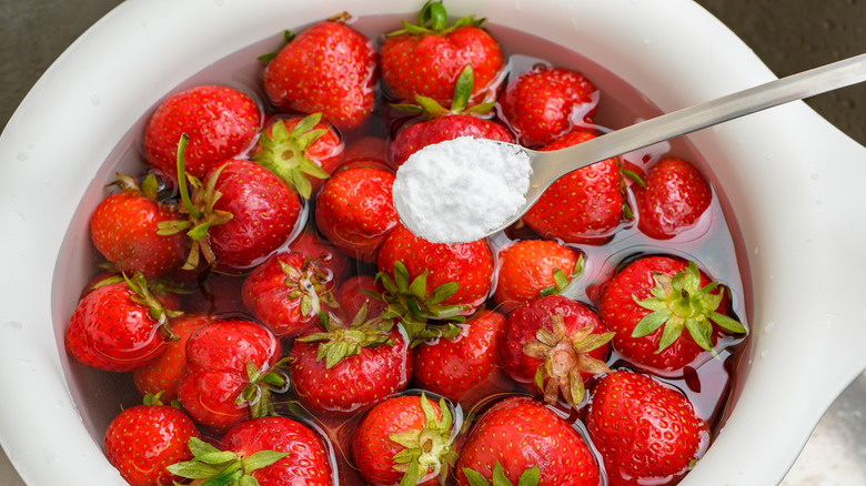 A spoon of baking soda over strawberries