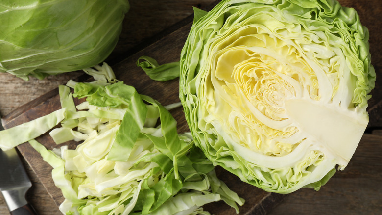 Partially cut green cabbage on a wooden cutting board