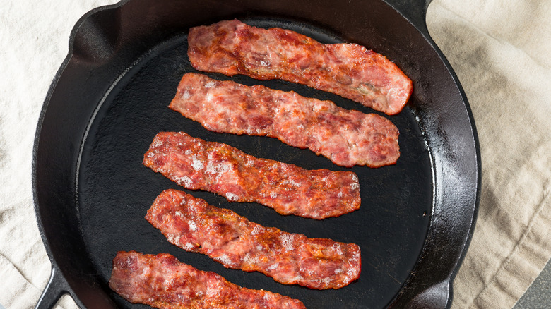 turkey bacon frying in a cast iron pan