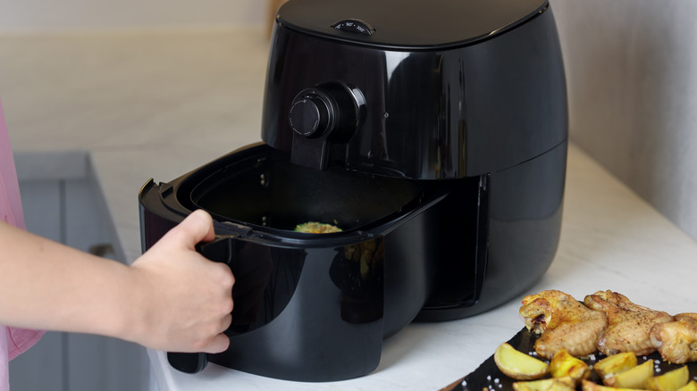 woman opening black air fryer