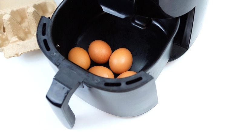 Whole brown eggs in a black air fryer basket