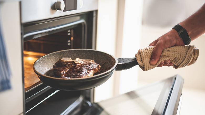 Steak on a pan being placed inside an oven