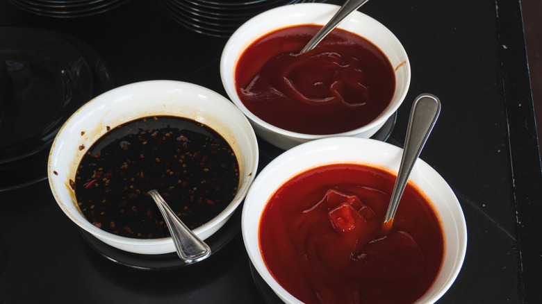 Various small white bowls of different sauces with spoons.