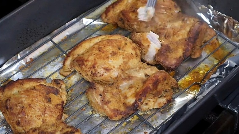 Few pieces of roasted turkey ribs on rack in pan with fork testing one piece.