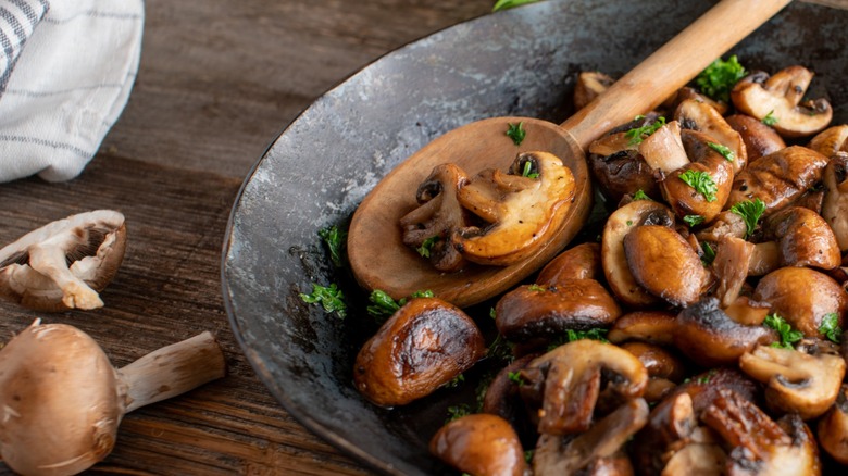 Delicious fried mushrooms with flat bread and herbs on the wooden table.