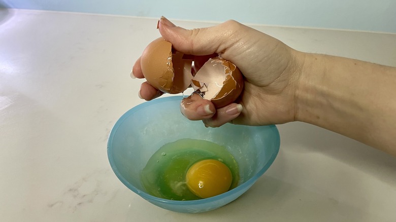 Hand cracking egg into dish