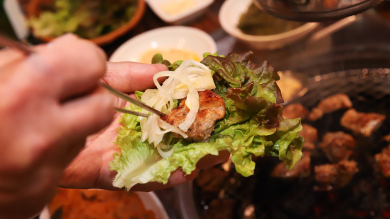 Hand holding a serving of Korean BBQ ssam