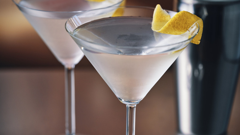 Two martinis with a lemon garnish.