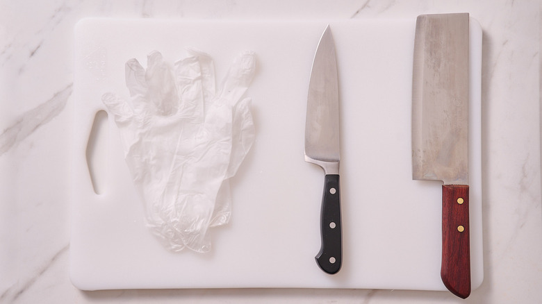 cutting board, knives, and gloves on a table