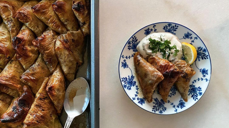 Plate of stuffed leek triangles next to tray of stuffed leeks.