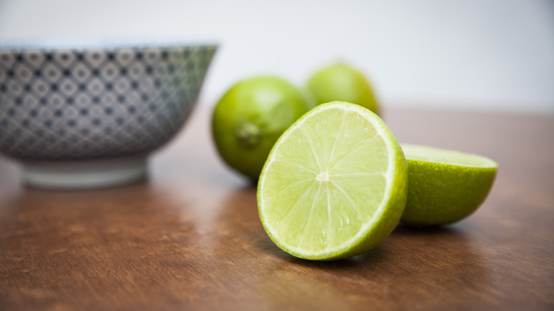 Limes sliced in half with bowl in background