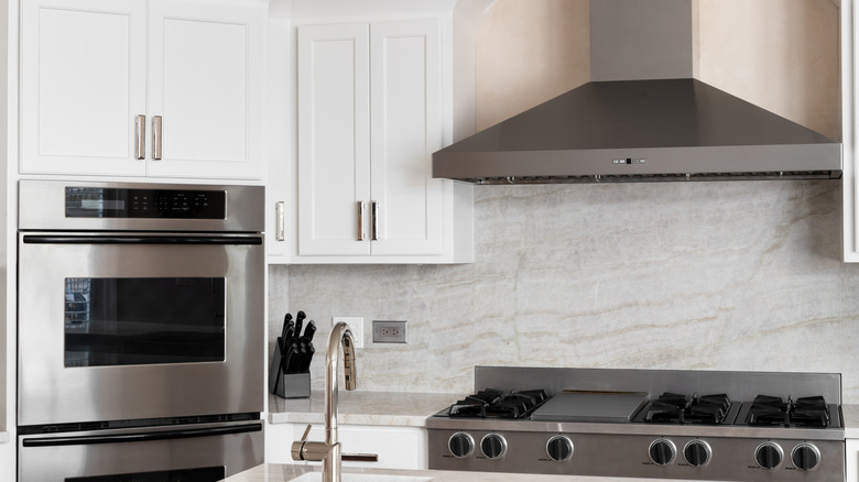 A minimalist kitchen with white cabinets and stainless steel appliances.