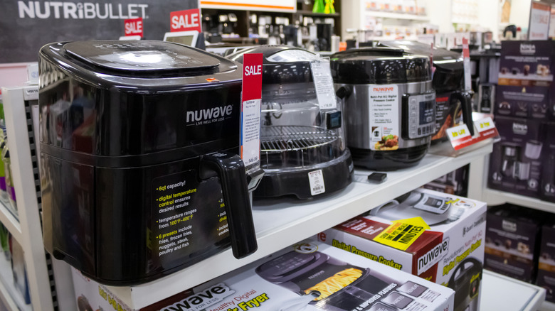Multiple air fryer models on a store display.
