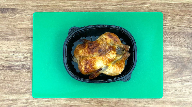 Whole rotisserie chicken in its packaging on a cutting board