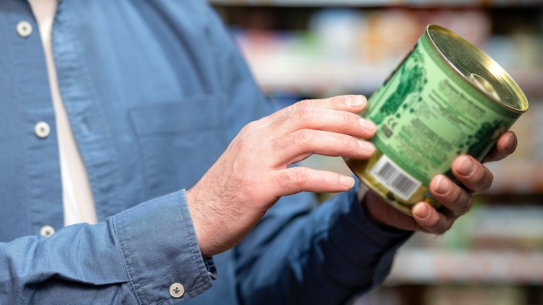 Person holding canned food with a green label