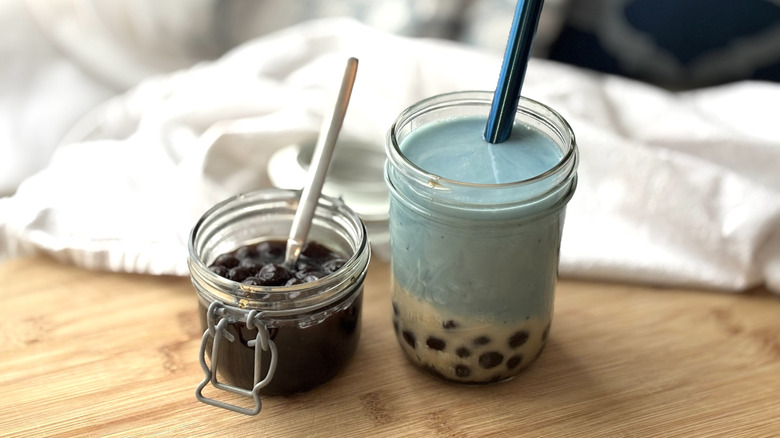 butterfly pea powder boba tea with jar of boba pearls