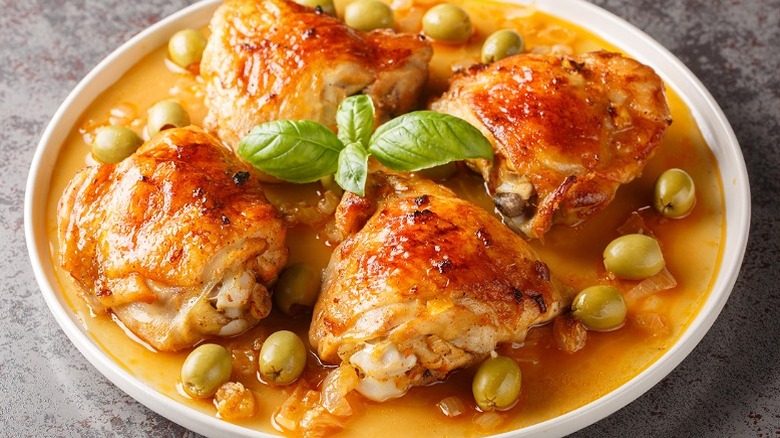 A plate of baked chicken garnished with green olives.