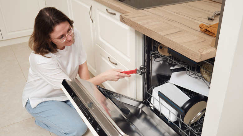 Woman repairing dishwasher