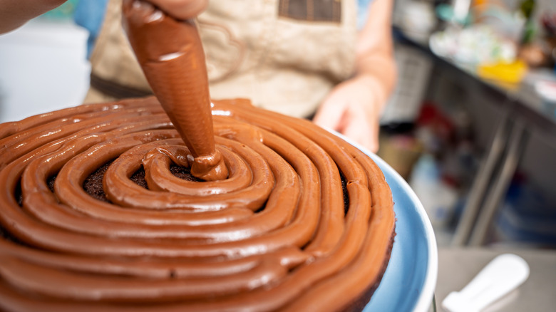 Frosting a cake with chocolate buttercream