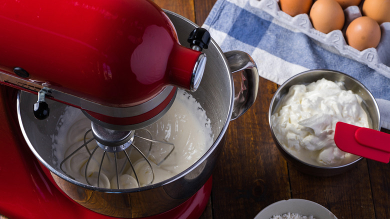 KitchenAid stand mixer in its signature red color blending eggs and cream