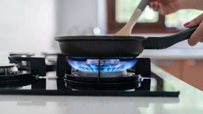 Gas flame underneath a pan on a stove.