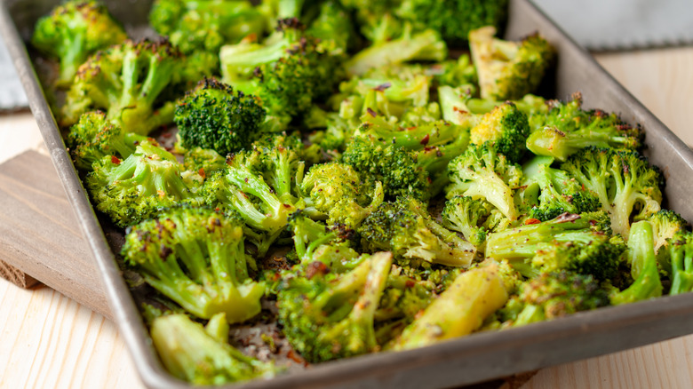 Oven roasted broccoli florets on an aluminum sheet pan with garlic and red pepper flakes