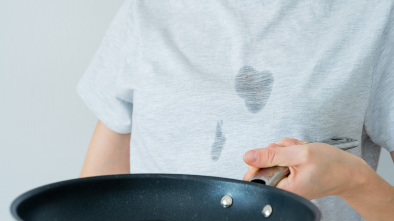 Person in butter stained t-shirt holding frying pan