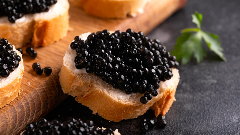 Slices of bread with black caviar on a rustic background.